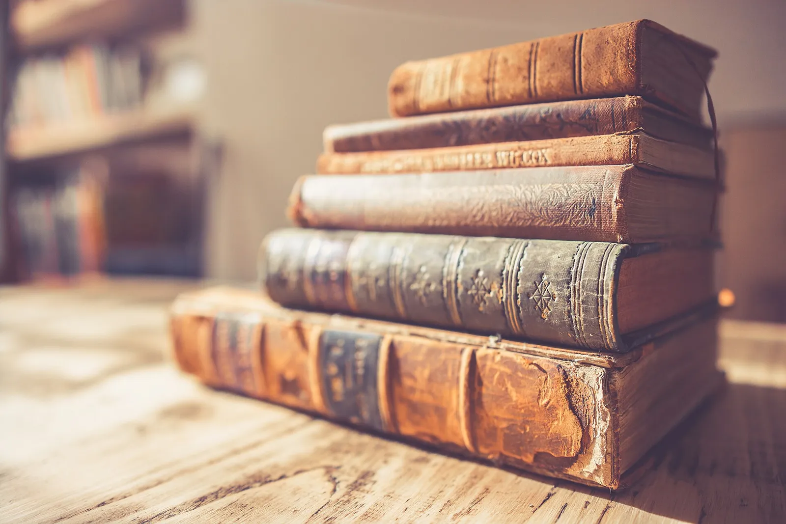 A stack of old leather-bound books on a wooden table